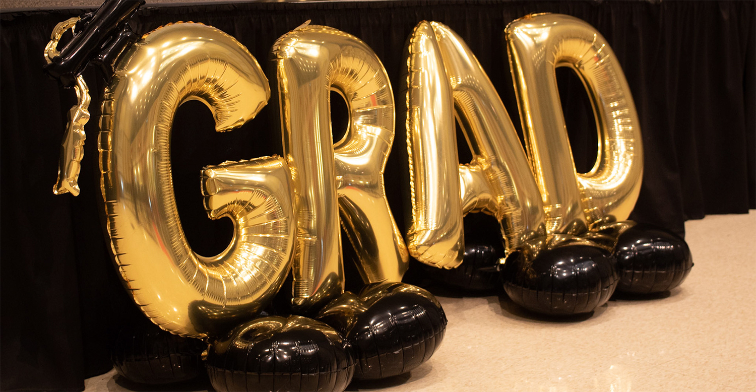 Golden balloons spelling grad, short for graduation or graduate