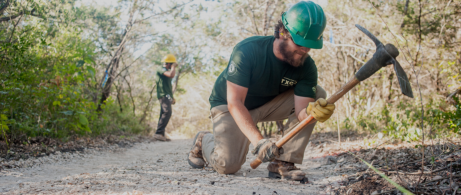 A conservation corps crew member building a trail.