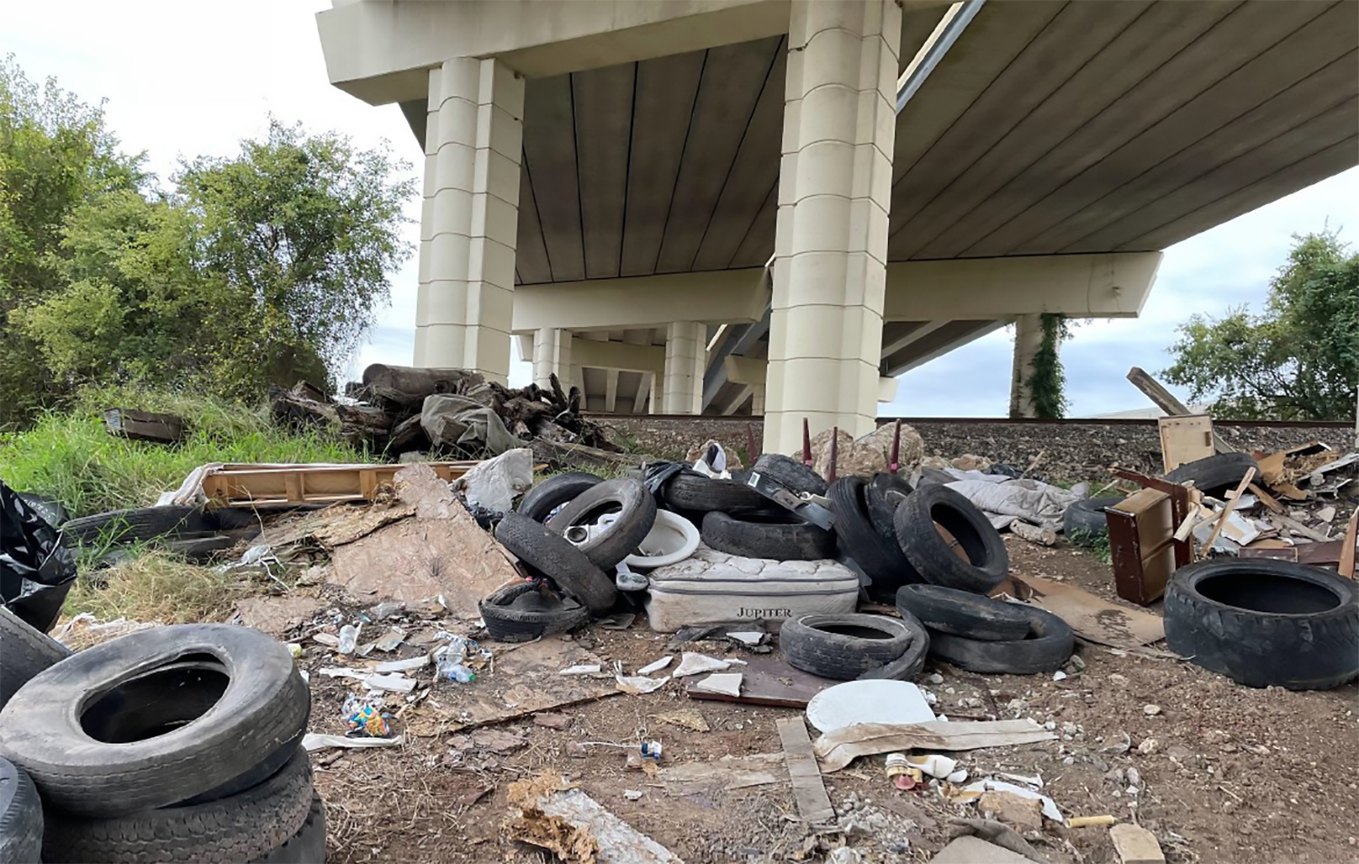 Tires and trash under a highway.