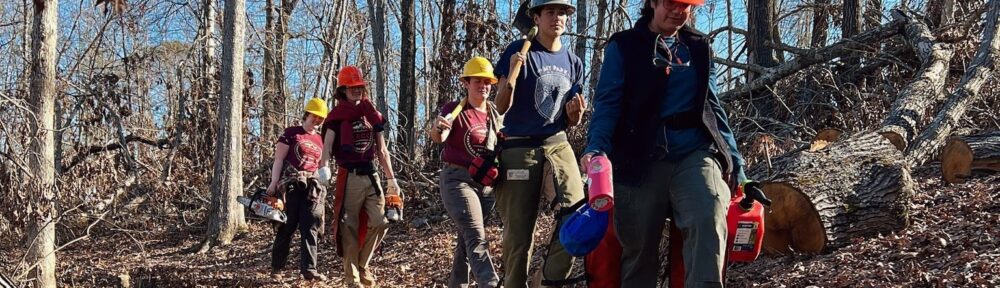 ARCC crew carrying in gear to project site along a forest trail.