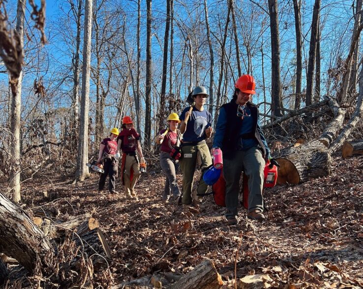 ARCC crew carrying in gear to project site along a forest trail.