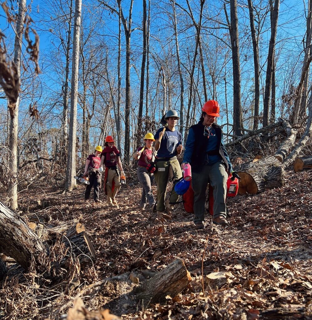 ARCC crew carrying in gear to project site along a forest trail.