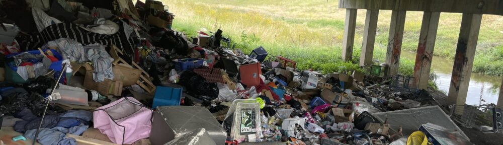 Trash piled up under an overpass.