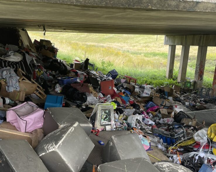 Trash piled up under an overpass.