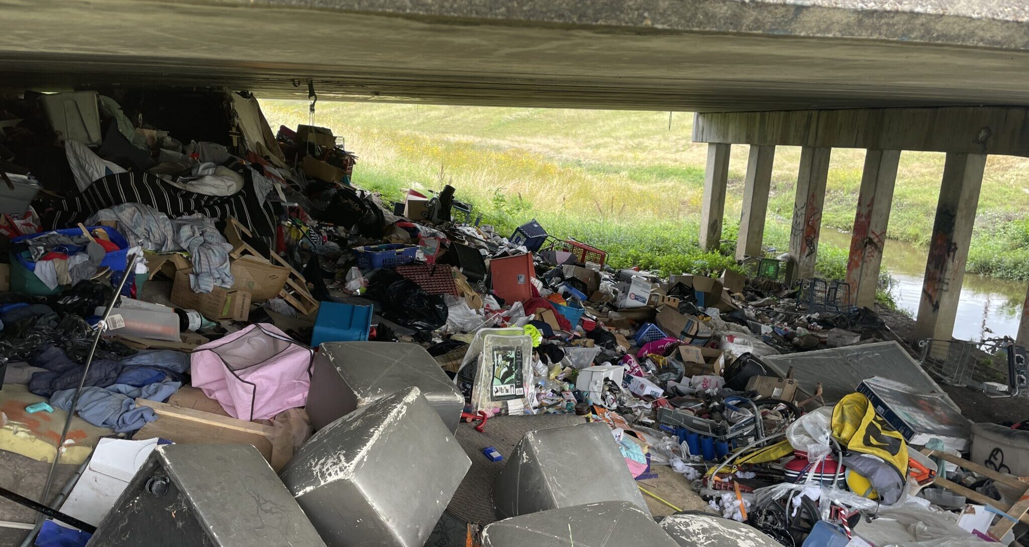 Trash piled up under an overpass.